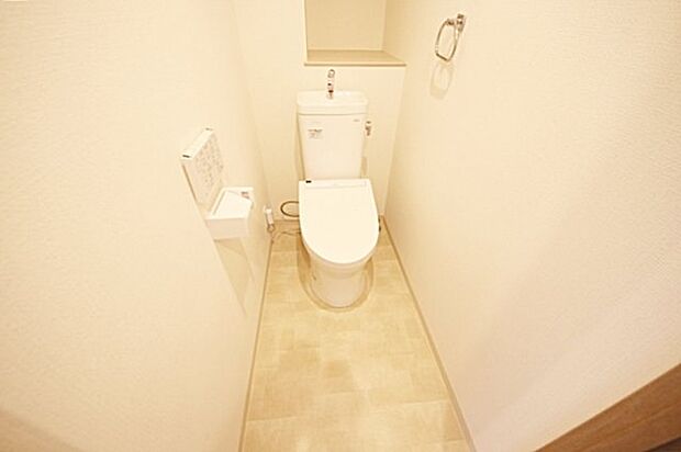 白を基調とした清潔感あるトイレ、後ろに設けた棚は物を取り出しやすいオープンタイプ