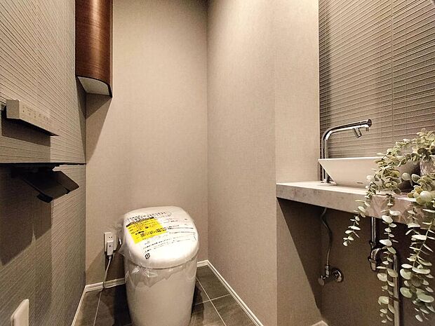 アクセントクロスが採用された、お洒落なトイレです。独立型の手洗いカウンターが備わっています。