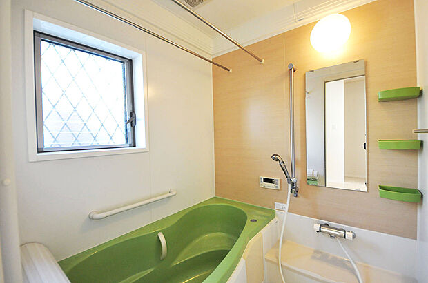グリーンの浴槽が爽やかなシステムバス。窓付きで換気がしやすいバスルームです。