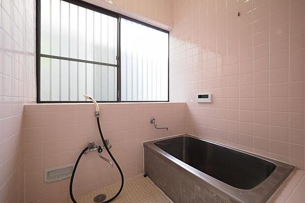 薄い桃色の温かみのあるバスルーム。採光・換気用の窓が大きく、明るい浴室となっております