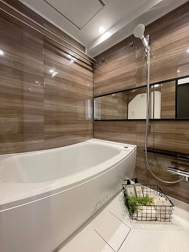 広々としたバスルームには美しいカーブと全身を包み込むような入浴感が特長の浴槽を新規設置。光沢のある木目調のパネルが、より一層くつろぎの空間へと誘います。