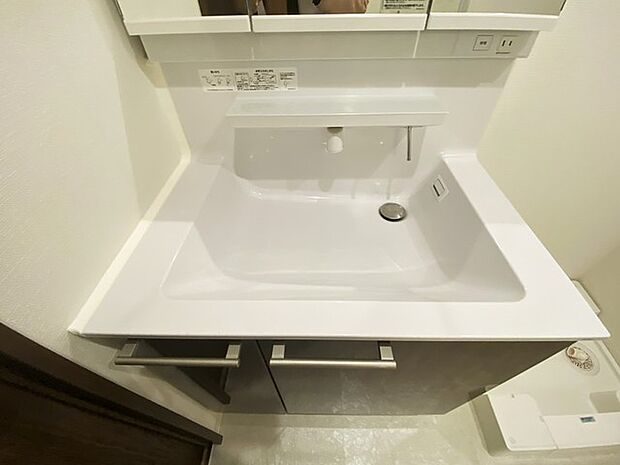 ワイドなボウルにハンドシャワー水栓が付いた洗面化粧台。 
