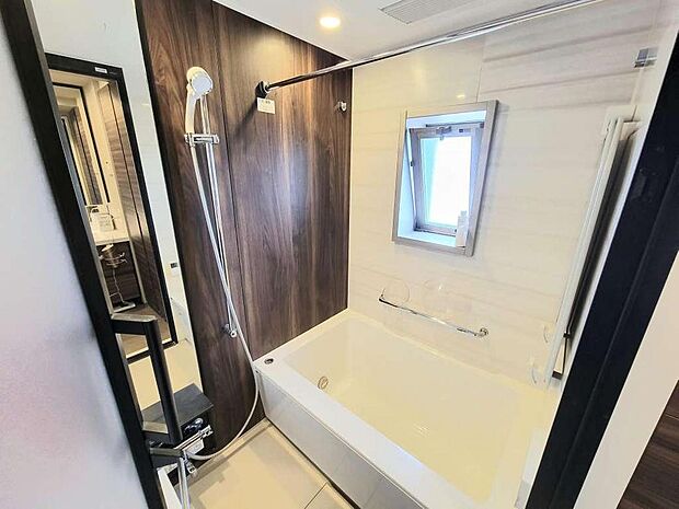 換気に最適な窓付き浴室。清潔感のあるシンプルなデザインの浴槽。浴室の壁は木目調パネルで高級感と落ち着いた雰囲気を演出しています。24時間換気、浴室乾燥機等、充実の機能が付いています