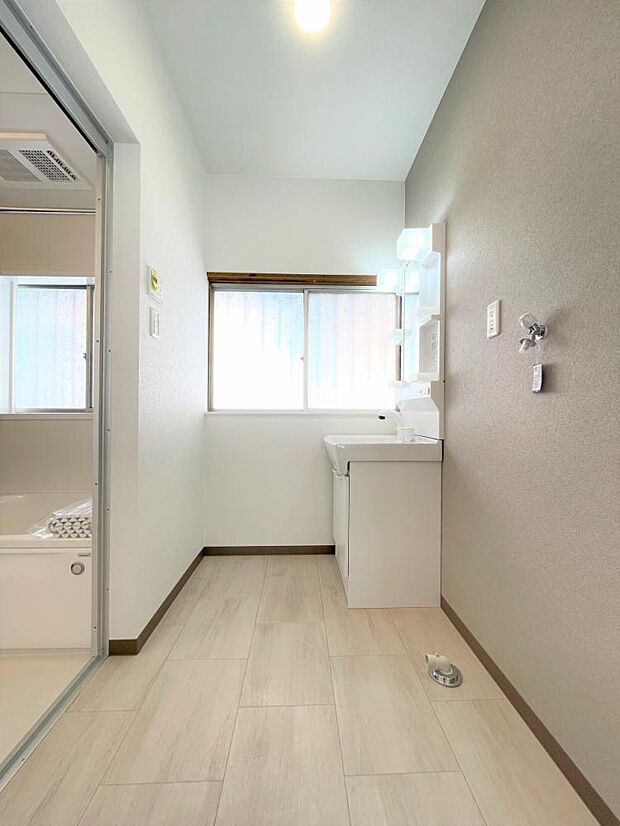 【リフォーム済写真】洗面所の写真です。床はクッションフロア、壁・天井はクロス貼りを行いました。洗面化粧台は新品に交換しました。