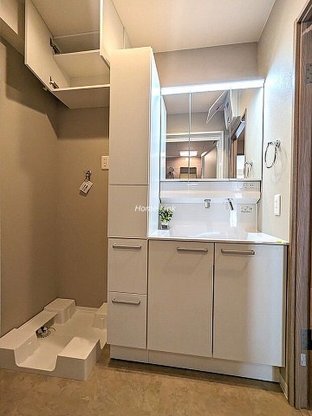 洗面化粧台は収納スペース豊富です。洗濯機置場の上部にも扉付きの収納が設置されています。