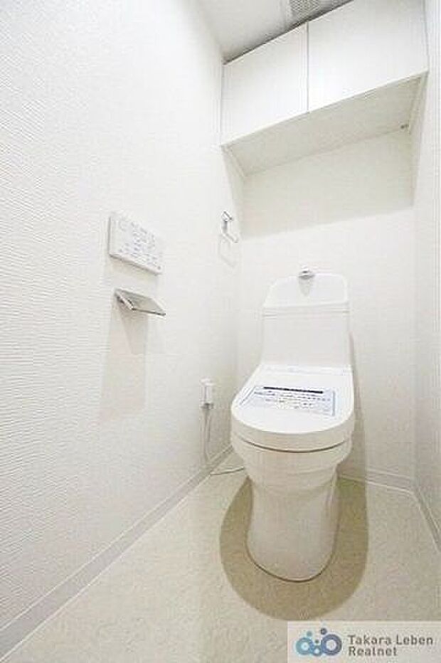 ウォシュレット機能付きのトイレは壁掛けリモコンの上位グレードを採用。上部に吊戸棚があり、掃除用具などの収納場所に困りません。