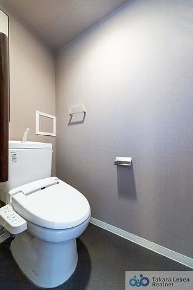 落ち着いた壁紙で清潔感のあるトイレ。トイレットペーパーホルダーとタオル掛けは標準で実装してます。背面には扉付きの棚があり、掃除用具などの収納場所に困りません。