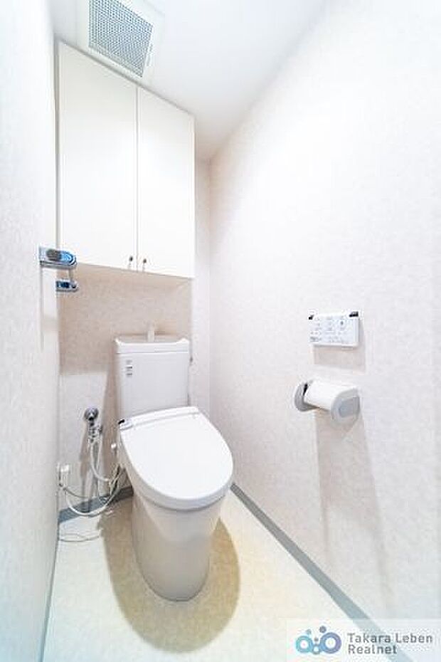 ウォシュレット機能付きのトイレは壁掛けリモコンを採用。限られた空間を広く見せる効果があります。上部に吊戸棚があり、掃除用具などの収納場所に困りません。