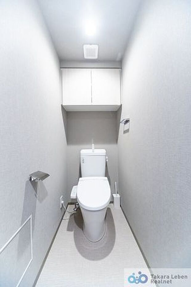 落ち着いた壁紙で清潔感のあるトイレ。トイレットペーパーホルダーとタオル掛けは標準で実装してます。上部に吊戸棚があり、掃除用具などの収納場所に困りません。