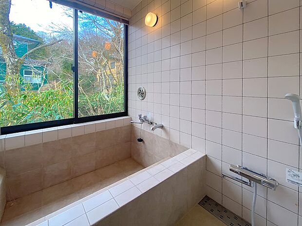温泉引込が可能な浴室です。石タイル張りの浴槽は腰掛スペースもあり、2人以上で入浴できるサイズ感です。