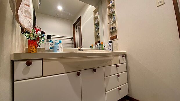 洗面脱衣スペース内には大きめの鏡、白を基調とした洗面台が配置されています。