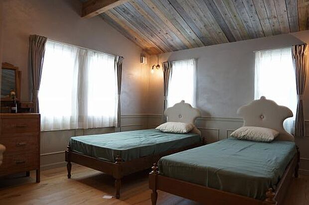 板張りの勾配天井と壁のテクスチャーペイントで、ちょっとしたリゾート気分を味わえる寝室