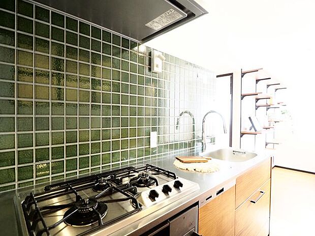 「食」の幸せを育むキッチンは心地よい空間に。印象的なグリーンのタイルをレイアウト。