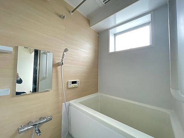 窓から自然光が届く明るい浴室。追焚・浴室乾燥機付き。