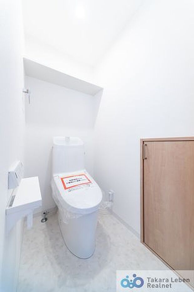 白を基調に清潔感のあるトイレ。トイレットペーパーホルダーとタオル掛けは標準で実装してます。上部に棚と、扉付き収納スペースがあり、掃除用具などの収納場所に困りません。