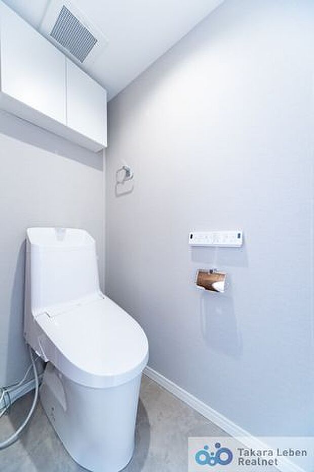 落ち着いた壁紙で清潔感のあるトイレ。トイレットペーパーホルダーとタオル掛けは標準で実装してます。上部に吊戸棚があり、掃除用具などの収納場所に困りません。