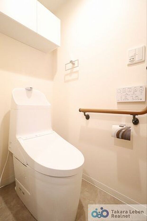 トイレの立ち上がりに便利な手すり付き。ウォシュレットリモコンは壁掛け仕様なのでスペースが広く感じられます。