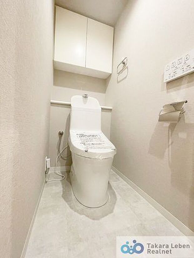 吊戸棚付き温水洗浄トイレ。リモコンは使用しやすい壁掛けタイプ。カウンターがあり、お洒落にデコレーションも出来ます。