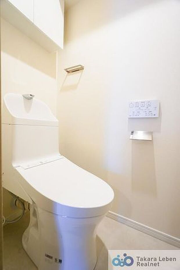 吊戸棚付き温水洗浄トイレ。リモコンは操作がしやすい壁掛けタイプです。