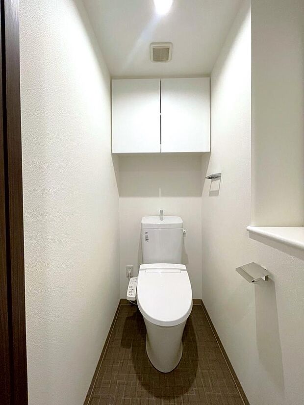 温水洗浄便座付きの清潔感あるトイレは、落ち着いた空間に。収納棚が設置されており、床にストックを置く必要がなく掃除も楽々。