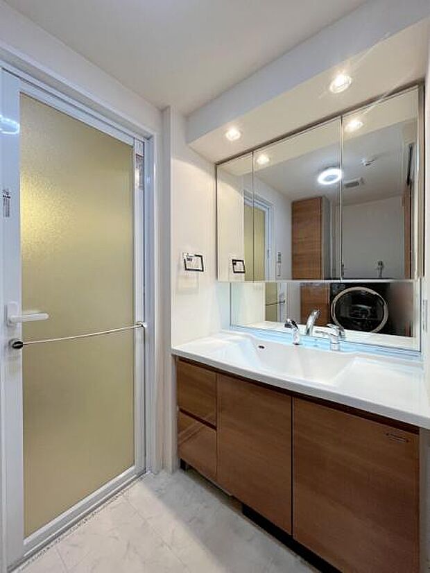 【脱衣所】三面鏡付き洗面化粧台。低めの位置にも鏡が設置されており、お子様でも使いやすい設計です