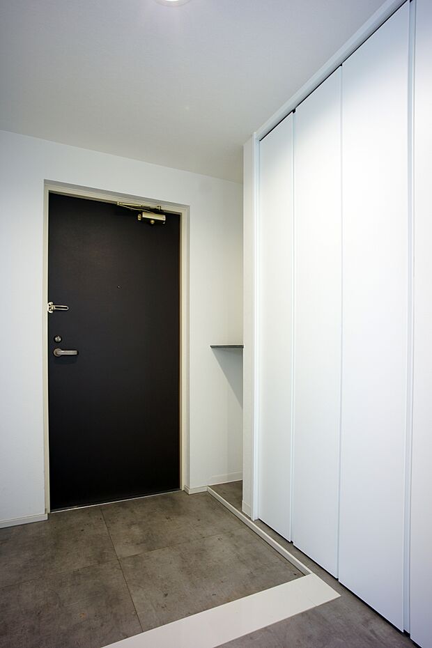 玄関の段差も低く、玄関収納も豊富です。白とモルタル材の床が魅力的な空間を演出しています。