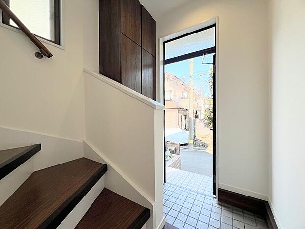 住まいの第一印象を決める玄関スペース、ウッド系の下足入れを使用し、高級感と清潔感を演出しました。小窓からの採光で明るい設計です。