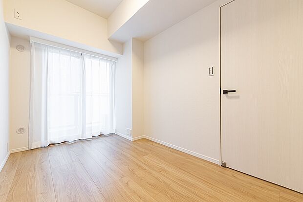壁紙、床材ともに明るい色合いで統一されているので、広く感じられる洋室