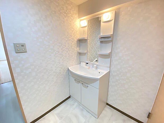 【洗面室】白を基調とした清潔感のある洗面室です。鏡横と洗面台下に収納があり、洗剤やお掃除グッズなどもすっきりとしまえます。リノベならではのタイルや照明にこだわった造作洗面台のご提案もお任せください。