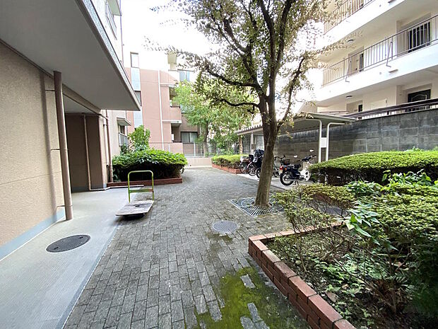 【外観】マンション敷地内には植栽があちこちに並んでいて、自然たっぷり感じられる住環境です。日本の都市公園１００選にも選出された服部緑地までは徒歩約２分、利便性と自然を兼ね備えた住環境となっています。