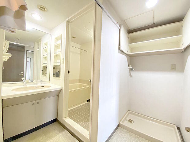 【洗面室】大きな鏡の付いた洗面台で毎朝の身支度もはかどります。鏡横の物入は可動３枚棚、洗濯機置き場上部には扉付き可動１枚棚がついていますので、お掃除グッズやタオルなどもすっきりとしまえます。