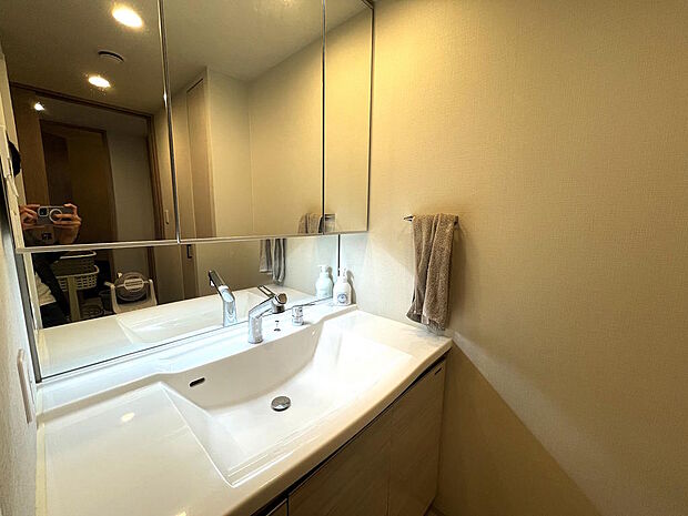 【洗面化粧台】３面鏡の明るい洗面化粧台です。鏡裏と洗面台下に収納があり、すっきりとした空間を保つことができます。タオルハンガーが設置されていて助かります。大きめのボウルで手洗いのものも洗いやすいです