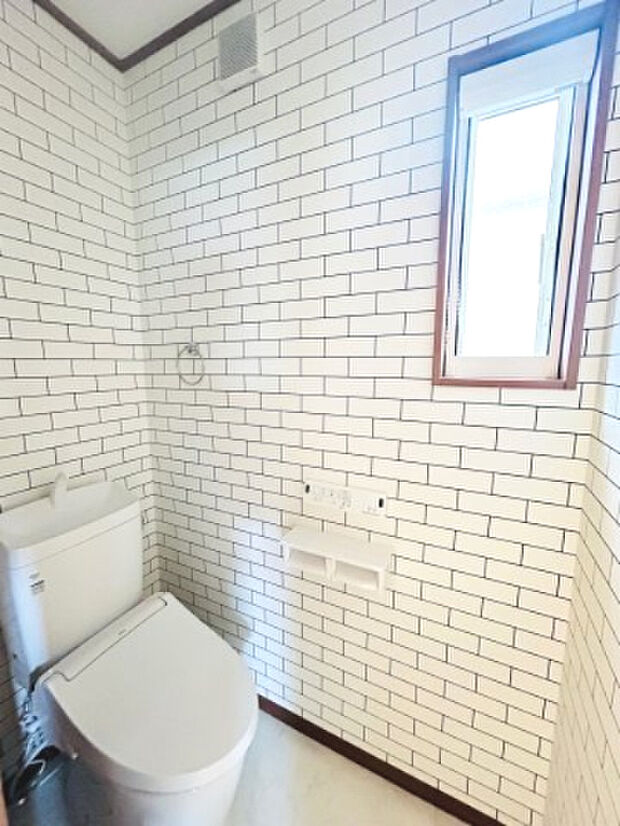 【トイレ】　タイル調のアクセントクロスでおしゃれなトイレ空間となっております。
