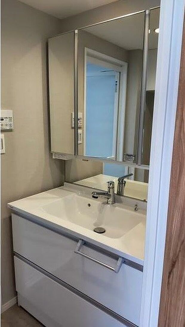 鏡の裏に歯ブラシなどのアメニティグッズなどを収納できる三面鏡タイプの洗面化粧台