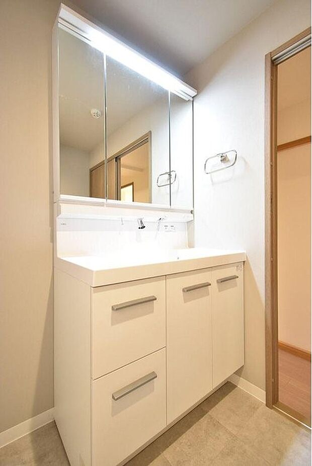 鏡の裏に歯ブラシなどのアメニティグッズなどを収納できる三面鏡タイプの洗面化粧台