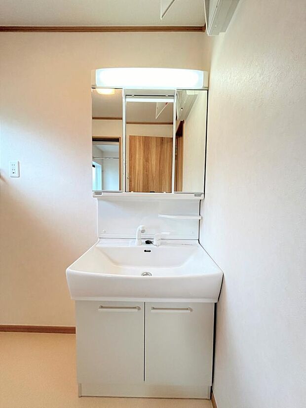 【リフォーム済】新品交換した洗面台には三面鏡が付いています。鏡の裏の収納は、3ｃｍ刻みでトレーの高さが変えられるのでたっぷり収納ができます。ＬＥＤ照明付きで明るく使いやすい洗面台です。