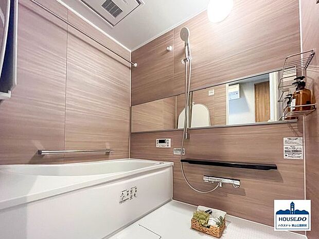 木目調で優しいイメージの浴室。浴室鏡は室内の広さを感じさせる横向きで配置されています