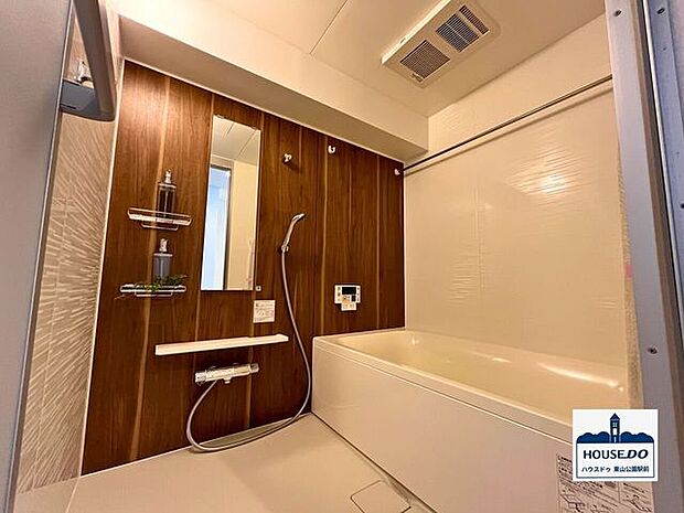 1面が木目調で優しいイメージの浴室。鏡は利便性の高い縦向きに設置されています