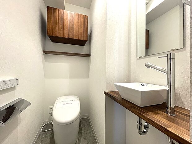タンクレスですっきりとしたデザインのウォシュレット付きトイレです。室内は天然無垢材の温もりを感じる落ち着いた上質な空間です。吊戸棚を備え、ミラー付の便利な専用手洗いスペースも付いています。