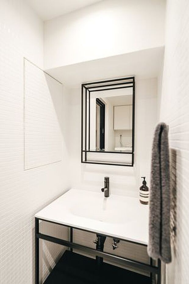 洗面：室内とは異なり白を基調とした明るいトーンで仕上げた水周り。壁は高級感のあるタイル張りです。
