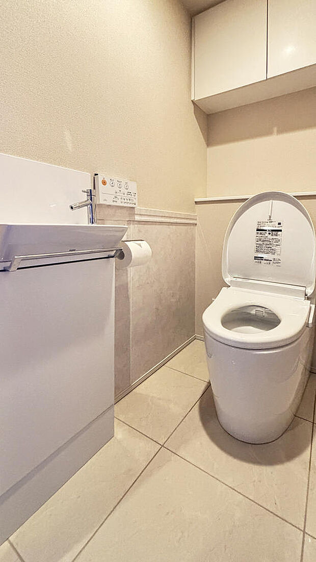 手洗い付きのトイレ。トイレットペーパーや小物が収納できる吊戸棚が配置されています。