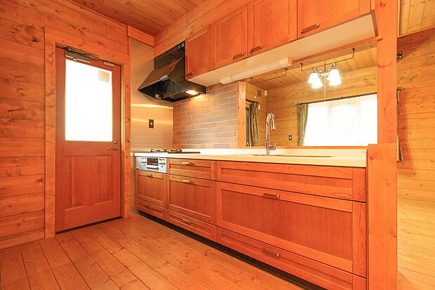 木の色合いに、白の天板がよく映えるキッチンは、奥のものが取り出しやすいスライド式収納を採用。