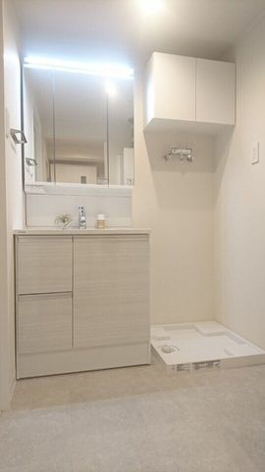 洗面台、横には洗濯機置き場（防水パン）、上部に小型の収納があります。
