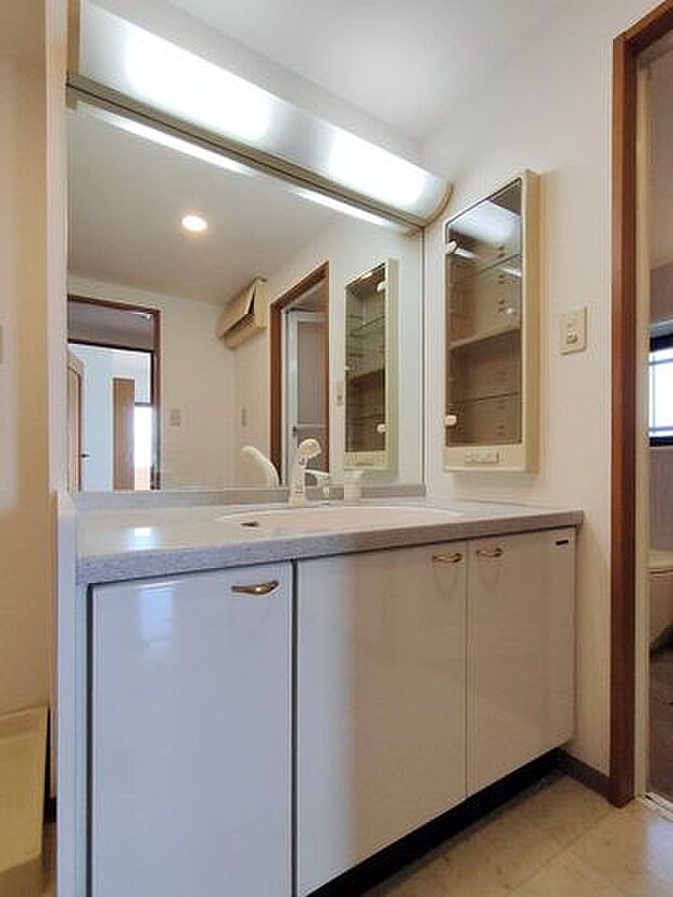 大きな鏡のワイドな洗面台。サイドにも収納スペースがあります。