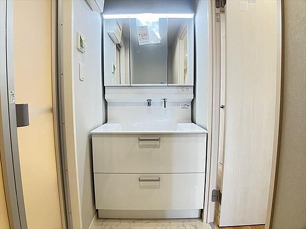 洗面台：ホワイトを基調とした洗面所で、三面鏡の裏や洗面台の下には収納スペースがあるので、散らかりがちな小物をスッキリと片付けることができます。