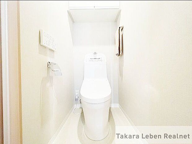 吊戸棚付き温水洗浄トイレ。明るめのクロスを使用し、圧迫感のない空間です。