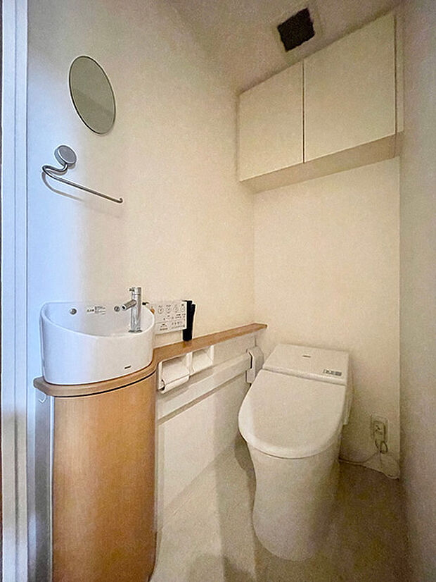 ウォシュレット一体型トイレ。タンクレスタイプでスッキリとした印象。便利な吊戸棚・手洗い場付き。