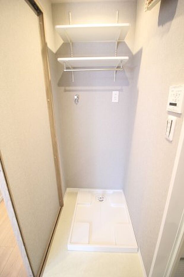 洗濯機置き場はこちら。新品の防水パンが置かれ、便利な棚も用意されています