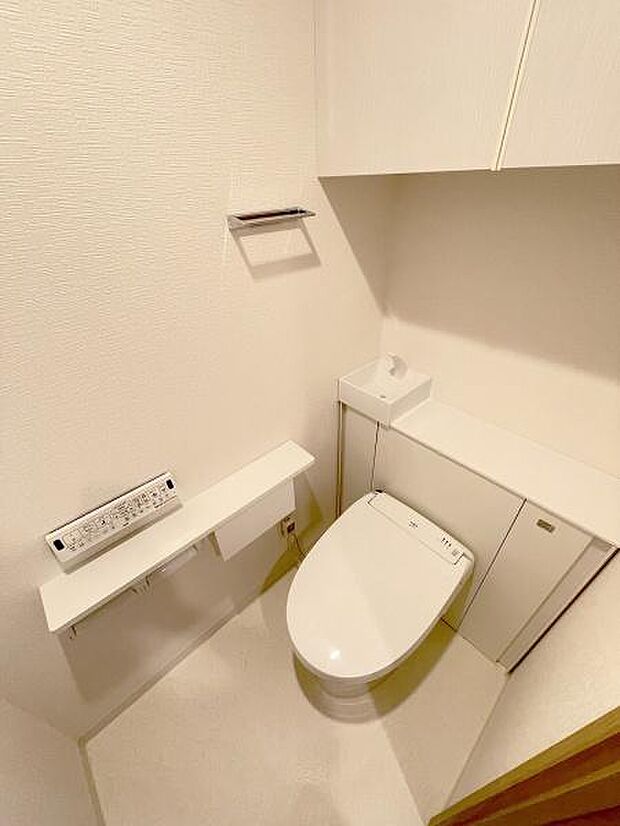 手洗い場のあるタンクレストイレ。温水洗浄便座の操作パネルは壁付けにし、見やすくしました。