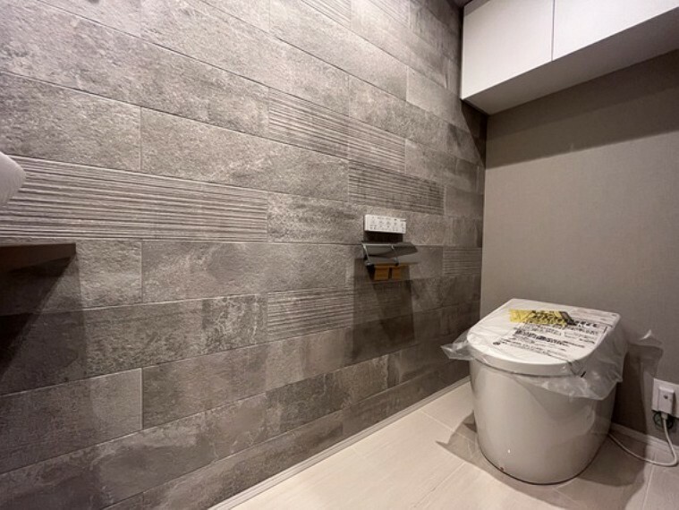 オシャレな石調の壁材、タンクレス仕様ですっきりした印象のトイレです